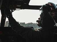 Im Gegenlicht sitzt ein Pilot im Cockpit und kontrolliert die Technik.
