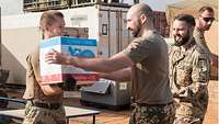 Vier Soldaten bilden eine Arbeitskette, sie übergeben einen Wasserkarton