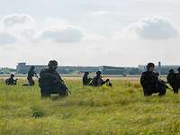 Soldaten sichern die Umgebung Neun Soldaten sind abgekniet im hohen Gras und sichern die Umgebung.