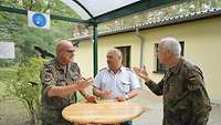Drei Soldaten stehen am Tisch und reden.