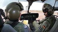 Zwei Bundeswehr-Piloten sitzen im Cockpit eines Hubschraubers und unterhalten sich