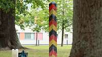 Die Grenzsäule steht auf einer Wiese, davor liegen Werkzeuge der Handwerker, die den Pfahl fest verankert haben