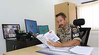 Ein Soldat sitzt an einem Schreibtisch und blickt in ein Buch für Disziplinar- und Strafrecht