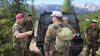 Mehrere Soldaten stehen auf einem Gebirgsweg vor einem Kettenfahrzeug.