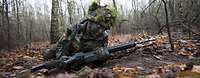 Ein Bundeswehrsoldat gleitet mit dem Gewehr G36 über den Waldboden