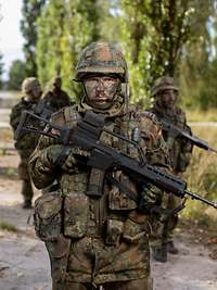 Soldaten der Bundeswehr im Gelände Mehrere bewaffnete Soldaten bewegen sich im Gelände.