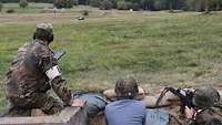 Leitender Schießausbilder mit Soldaten und Gästen bei der Schießausbildung.