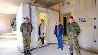 Mehrere Menschen stehen vor einem sichtbar abgetrennten Raumsegment