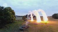 Ein Panzer im Gelände schießt Nebelgranaten