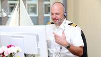 Das Bild zeigt Kapitän zur See Panke vor einem Bildschirm und mit Headset bei einer Online-Beratung