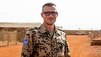 Ein Soldat steht in einem Camp und blickt in die Kamera