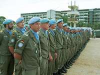 Angetretene Soldaten mit blauen Baretts stehen in mehreren Reihen vor einem Gebäude.