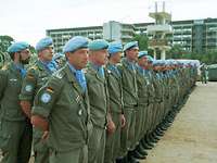 Angetretene Soldaten mit blauen Baretts stehen hintereinander vor einem Gebäude.