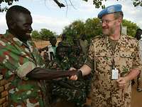 Deutscher Soldat reicht einem nordsudanesischen Kameraden die Hand.