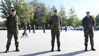 Drei Soldaten stehen auf einem Appellplatz in weitem Abstand voneinander. 