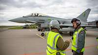Ein deutscher Hauptfeldwebel und ein britischer Offizier im Gespräch vor einem bemannten, britischen Eurofighter.