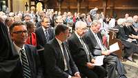 Geladene Gäste sitzen zahlreich den Kirchenbänken
