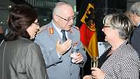 Generalleutnant Hans-Werner Fritz steht in der Mitte zwischen zwei Damen und unterhält sich