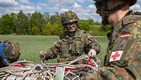 Three soldiers prepare to transport material by helicopter using a cargo loading net.