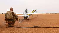 Afghanistan: A soldier crouches behind the unmanned aerial vehicle, which has already been placed onto the catapult.