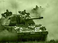The armoured self-propelled Panzerhaubitze 2000 howitzer is a primary weapon of the artillery. Two armoured self-propelled howitzers drive at speed, one behind the other, across a training area, whirling up dust.