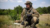 A soldier with radio equipment observes the artillery’s target area.