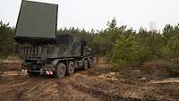 In a small clearing a truck-mounted COBRA Counter-Battery Radar stands ready for use.