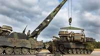 Servicemen lift an entire powerpack from a main battle tank’s engine compartment.