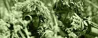 The image shows two armed infantry soldiers: A platoon leader is giving instructions to a soldier.