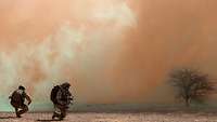 On operations in Mali, two infantry soldiers provide security in the extreme heat. Dust swirls.