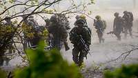 Infantry soldiers move to cover across an open area.