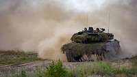 A Leopard 2 MBT traverses open ground.