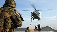 SOF soldiers rappel from a helicopter onto a rooftop and secure it.