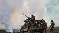 A SERVAL vehicle with embussed soldiers stands in an open area.