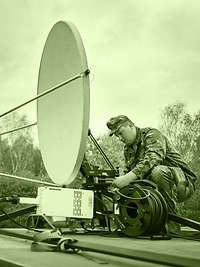 The signal corps establishes and maintains communications. A soldier setting up a satellite antenna on a rooftop.