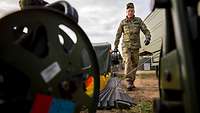 A soldier holding a cable reel with the left hand, speedily unwinding communication cable.