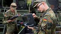 Two soldiers preparing two telephones to be used at a command post.