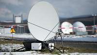 A cordoned-off satellite dish in lightly snow-covered grass. 