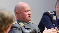 Oberst Ralph Malzahn sitzt zwischen zwei Personen und unterhält sich