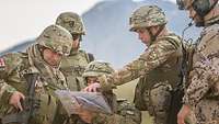 Fünf Soldaten stehen zusammen und planen die Route anhand einer Karte