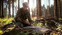 Ein Soldat baut ein Versteck im Unterholz eines Waldes.
