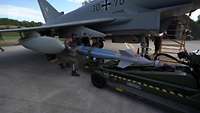 Soldaten befestigen eine Bombe an einem Kampfflugzeug vom Typ Eurofighter