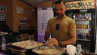 Ein Soldat steht hinter dem Tresen und portoniert Pizzateig