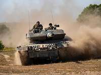 Ein Kampfpanzer Leopard fährt im Gelände und wirbelt Staub auf