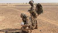Zwei Soldaten in öder Landschaft, einer funkt, einer sichert