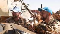 Zwei Soldaten schauen einen Motor an.