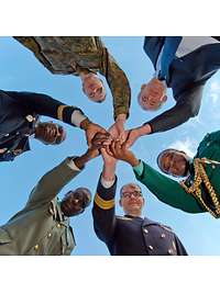Symbolbild Bundessprachenamt Sechs Personen, darunter Soldatinnen und Soldaten und Zivilisten, reichen im Kreis stehend sich die Hände.