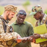 Drei Männer unterhalten sich, der Nicht-Uniformierte dolmetscht zwischen den beiden Soldaten.