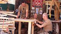 Unteroffizier Thomas K. und zwei Soldaten arbeiten an einem Holzgestell