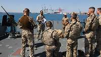 Mehrere Soldaten stehen am Oberdeck und besprechen die abgeschlossene Übung